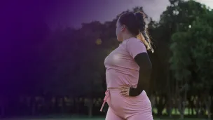 Plus-size woman exercising outdoors while looking towards at city skyline.