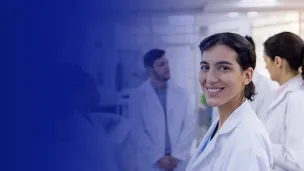 Smiling female medical professional with co-workers working in the background of a laboratory.