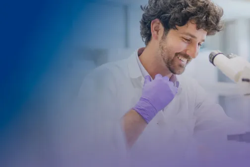 Male laboratory professional looking under a microscope in a laboratory.