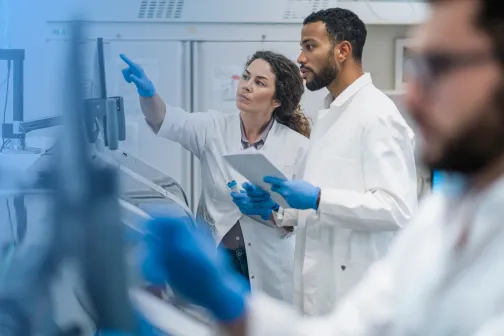 Two laboratory professionals collaborating while examining laboratory equipment.